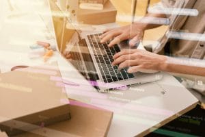 Woman typing on laptop sitting on messy desk